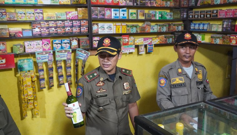 Petugas Satpol PP melakukan penyitaan minuman beralkohol yang dijual warung Jamu