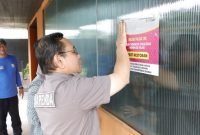 Fahmi Faisuri, Kepala Bidang Wasdal pada Bapenda Kabupaten Tangerang nampak yang memasang stiker pemberitahuan disalah satu restoran yang menunggak pajak, Jumat (21/02/2025)