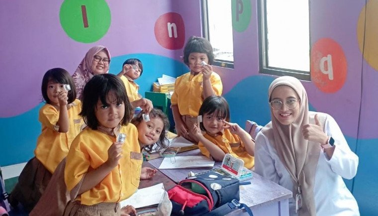 Tim medis puskesmas Cisauk berpose dengan anak sekolah usai memberi obat cacing